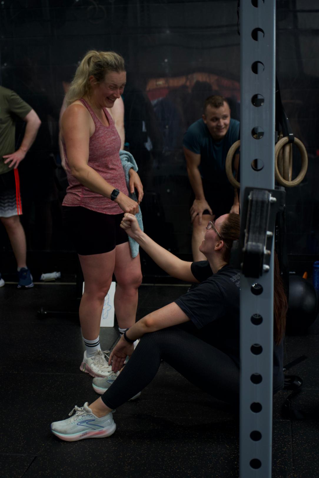 A coach kneeling beside a member to adjust her position